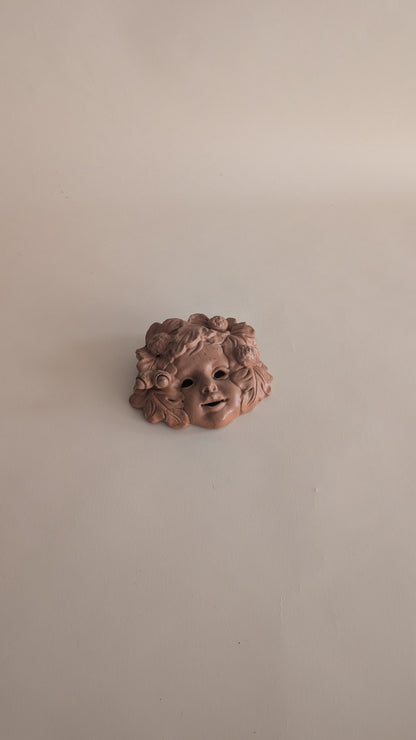 Masque mural vintage en terre cuite – visage d’enfant fleuri