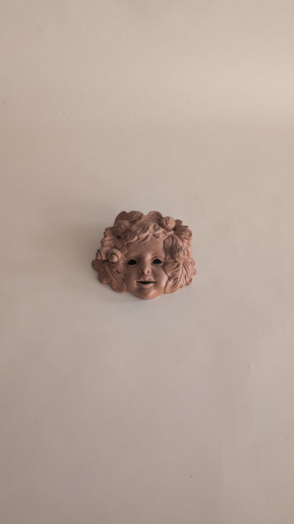 Masque mural vintage en terre cuite – visage d’enfant fleuri